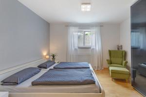 a bedroom with two beds and a green chair at Ferienwohnung Emilia, 36qm in Münsingen