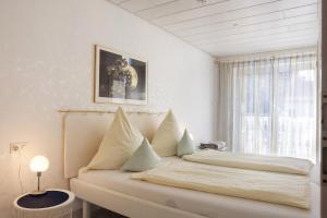 a white bedroom with a bed with a window at Ferienwohnung am Schlosssee in Salem