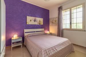 a bedroom with a bed and a purple wall at Villa Bartolomeo in Modica +27 photos