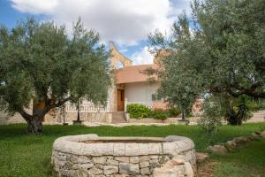 a building with a stone wall and two trees at Villa Bartolomeo in Modica