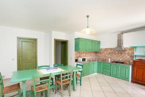 a kitchen with green cabinets and a table and chairs at Villa Mula 1 in Orosei