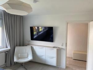 a living room with a white chair and a tv on a wall at Ferienwohnung Edelweiss am Steinberg in Goslar mit Terrasse und Garage in Goslar