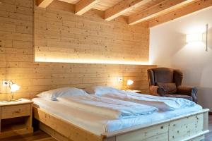 a bed in a room with a wooden wall at Hotel Residence Gardena Dolomites in Santa Cristina Gherdëina
