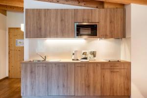 a kitchen with wooden cabinets and a sink at Hotel Residence Gardena Dolomites in Santa Cristina Gherdëina