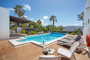 a swimming pool with two chairs and a table at Casa Margarita in Lanzarote
