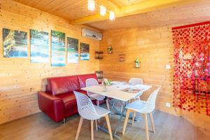 a dining room with a red couch and a table at Le Chalet Houda et spa en option in Nîmes