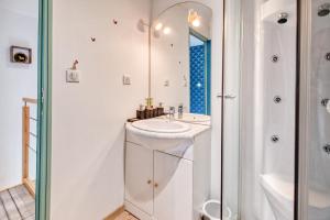 a white bathroom with a sink and a shower at Logement Le Buffet De La Gare in Falgueyrat