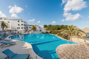 a swimming pool with chairs and umbrellas at a resort at White Sands 4.20 in Arenal d'en Castell