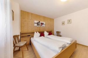 a bedroom with two white beds and a chair at Moar im Rumsein - Apt Saltenblick in Terlano