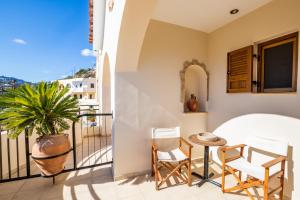 a balcony with chairs and a table and a plant at Petra Studios in Karpathos