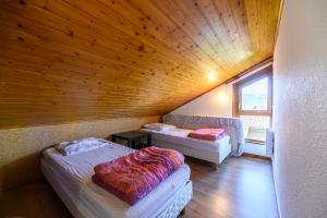 two beds in a room with a wooden ceiling at Les Chalets Du Pres D'amont in Vagney