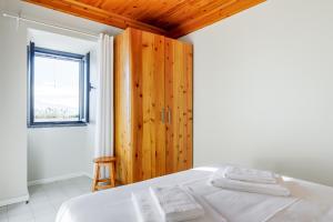 a bedroom with a white bed and a window at Casa da Praya in Horta