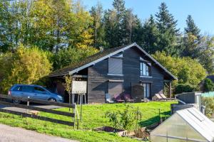 a house with a car parked in front of it at Les Chalets Du Pres D'amont in Vagney