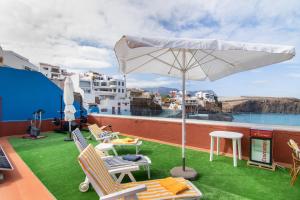 a patio with chairs and an umbrella on a roof at Vv Suite Las Velas in Gáldar