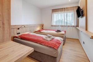 two beds in a room with a table and a television at Chalet Kb in Livigno