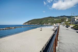 a beach with benches and the ocean on a sunny day at Appartamento Bilocale Moneglia 37 in Moneglia