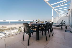 a dining table and chairs on a balcony with the beach at Beachfront Atlantic Sunset A07 in Óbidos
