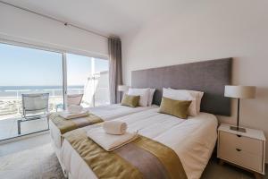 two beds in a bedroom with a large window at Beachfront Atlantic Sunset A07 in Óbidos