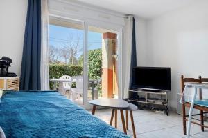 a bedroom with a bed and a tv and a balcony at Appartement Du Golf - Pornic 1 in Pornic