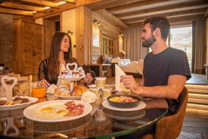 a man and a woman sitting at a table with food at Le Chalet Suite Livigno in Livigno