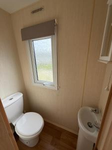 a small bathroom with a toilet and a sink at Sunnymede G20 with Hot Tub - pet friendly, Wifi, bed linen - Meadow Lakes Caravan & Lodge Hire in Ingoldmells +3 photos