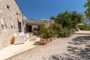 a patio with white chairs in front of a building at Trullo Cielo Cielo in Alberobello