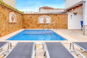 a swimming pool with two loungers next to a stone wall at Villa Pintor in Port de Pollensa