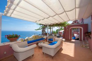 a patio with a pool and chairs and the ocean at Luxury Villa Soleluna con jacuzzi in Praiano