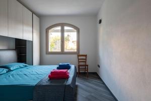 a bedroom with a bed and a chair and a window at Appartamento Latorre in Bari Sardo