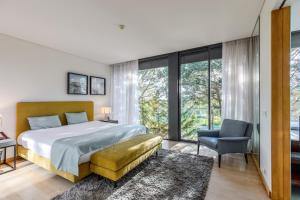 a bedroom with a bed and a chair and windows at Tróia Villa Paradise in Troia +27 photos