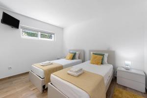two beds in a white room with a tv at Refugio Das Vinhas in Celorico de Basto +25 photos