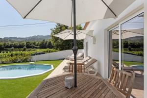 a patio with an umbrella and a swimming pool at Refugio Das Vinhas in Celorico de Basto