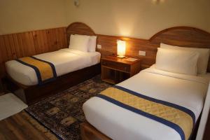 a hotel room with two beds and a lamp at Norbu Lingka Resort in Tongsa