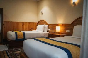 two beds in a hotel room with wooden walls at Norbu Lingka Resort in Tongsa