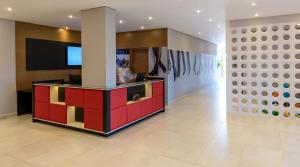a lobby with a colorful counter with a tv on a wall at ibis Styles Birigui in Birigui
