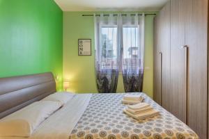 a bedroom with a bed with green walls and a window at Maison Emozioni Terrace in Limbiate