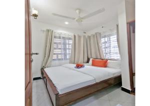 a bedroom with a white bed with orange pillows at Salpat Camp Lodge in Moshi