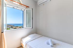 a bedroom with a bed and a large window at Anemologio 303 Tinos in Agios Ioannis