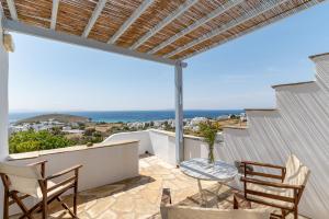 a patio with chairs and a view of the ocean at Anemologio 303 Tinos in Agios Ioannis
