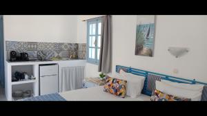 a bedroom with a bed and a kitchen with a window at Pico Bello Patmos 30 in Patmos +19 photos