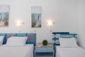 a bedroom with two beds and a table with a plant on it at Pico Bello Patmos 30 in Patmos