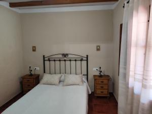 a bedroom with a bed with white sheets and two night stands at Casa Villazo 2 in Málaga