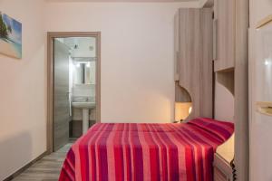 a bedroom with a bed with a red striped blanket at Monolocale Arredato - Le Terrazze in Ribera