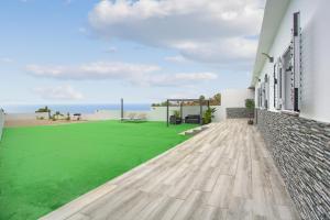 a house with a green lawn in front of the ocean at Villa Candelaria in La Matanza de Acentejo