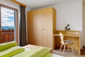 a bedroom with a bed and a desk and a window at Forchnerhof Apt Rose in Maranza