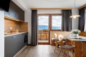 a kitchen with a table and chairs with a view at Forchnerhof Apt Rose in Maranza
