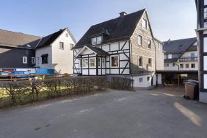 a black and white house with a driveway at Ferienwohnung Huckelberg in Schmallenberg