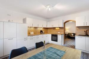 a kitchen with white cabinets and a wooden table at Ferienwohnung Huckelberg in Schmallenberg