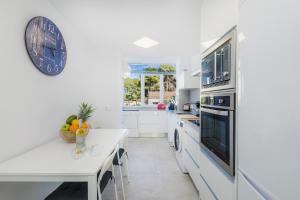 a white kitchen with a table and a clock on the wall at Apartamento La Pergola in Font de Sa Cala