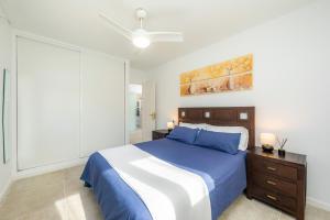 a bedroom with a blue and white bed and a ceiling fan at Apartamento La Pergola in Font de Sa Cala